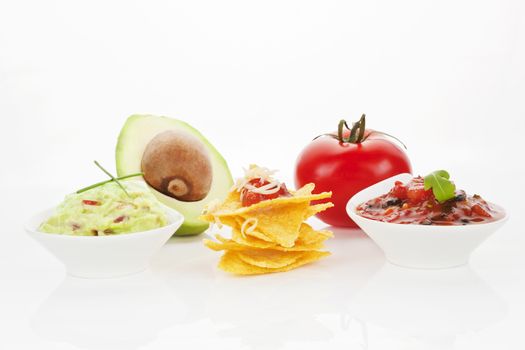 Nachos with guacamole and tomato dip and fresh avocado and tomato isolated on white background.