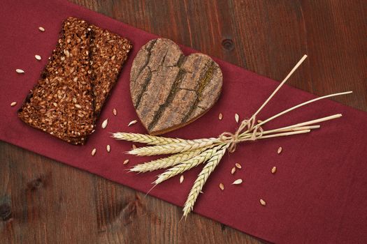 I love dark bread. Healthy eating. Dark bread slice with wooden heart shape and bunch of wheat.