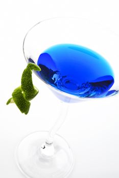 Blue delicious cocktail with lime garnish in cocktail glass isolated on white background.