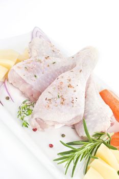 Chicken thighs with fresh vegetables on white tray. Cooking still life.