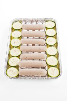  White bratwurst sausages with zucchini on grill tray isolated on white. Barbecue concept.