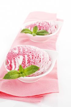 Cherry ice cream in bowls with fresh mint leaf on pink serviette isolated on white background.