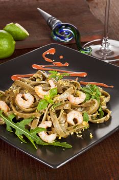 Pasta with shrimps served on a black plate. Luxurious dining.