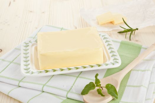Diary product. Butter on kitchen towel on wooden table with wooden spoon and fresh herbs. 