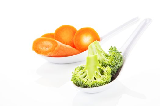 Broccoli and carrot pieces on white spoon isolated on white background.