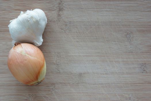 An onion and a garlic clove on top of a cutting board