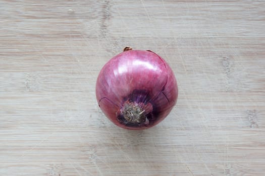 A solo red onion on top of a cutting board