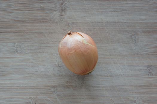 A solo white onion on top of a cutting board