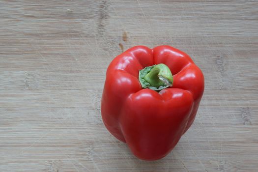 A solo red pepper standing on a cutting board