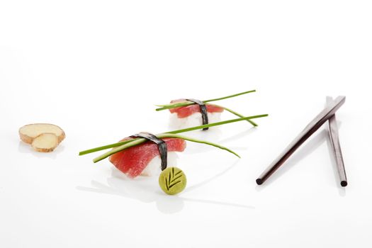 Sashimi sushi pieces with ginger, chopsticks, wasabi and chive isolated on white background.