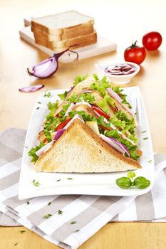 Tasty sandwiches with fresh vegetables on wooden table with tomatoes, onion, herbs and ketchup.