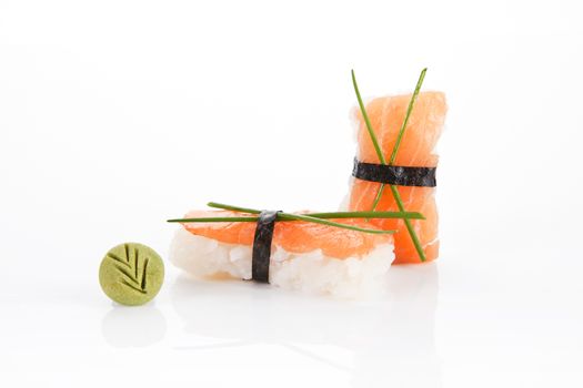 Nigiri sushi with salmon and wasabi leaf isolated on white background.