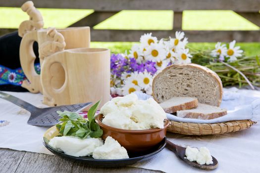 Traditional cheese on organic farm with herbs and wooden cups with traditional slovak milk product zincica. 