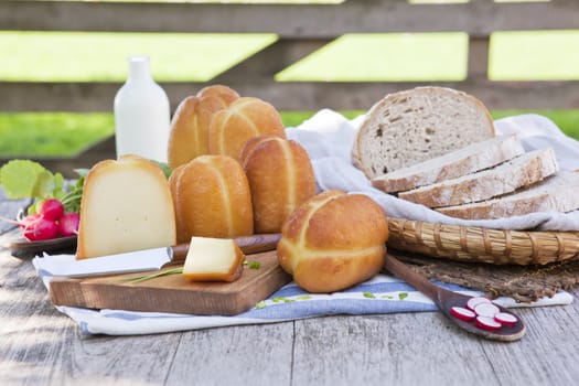 Traditional organic smoked cheese with fresh vegetables, milk and bread in background.