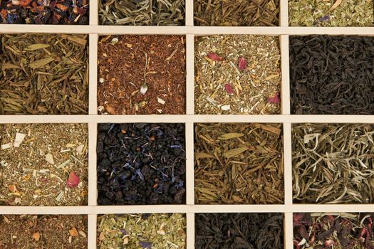 Various dry tea leaves - green, black, rooibos in wooden box.