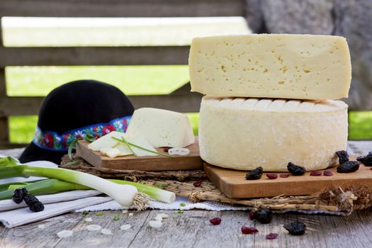 Big pieces of traditional white cheese on organic farm with fresh vegetables and dried fruits. 