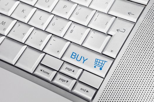 Silver keyboard with shopping cart icon and BUY text on keys. E commerce concept.