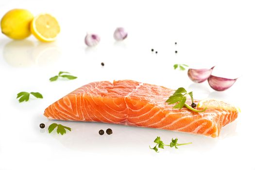 Delicious salmon steak with lemmon, parsley and garlic isolated on white background.