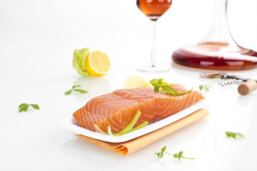 Delicious fresh salmon steak arrangement with lemon, parsley and wine isolated on white background.