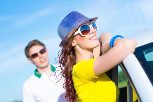 young attractive woman in sunglasses and hat stands next to a car, a close-up portrait