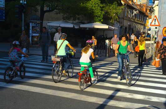 LUJBLJANA, SLOVENIA - SEPTEMBER 9, 2013: Unidentified people crossing street and riding bicycles on the street of Ljubljana. The downtown quarter usually attracts lots of tourists.