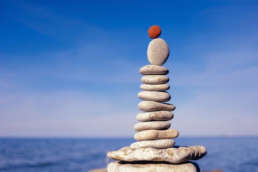 Balance of red stone on the top of stack of white pebbles