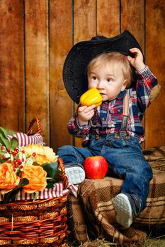 Little Cowboy on a farm in a hat and jeans after harvest