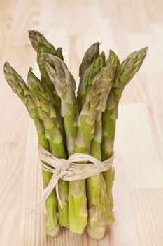Fresh asparagus bundle on wooden background. Culinary eating.
