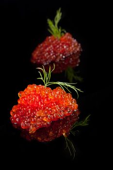 Luxury food. Caviar isolated on black background decorated with dill.