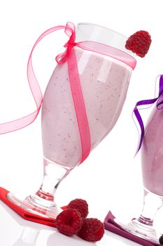 Raspberry yogurt shake with fresh raspberries decorated with pink ribbon isolated on white background. Luxurious summer drinks.