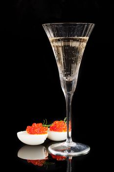 Caviar in egg with dill and champagne in glass isolated on black background. Luxury concept. 