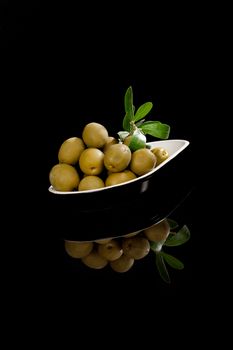 Green olives isolated on black background. Culinary appetizer.