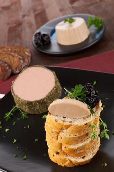 Delicious pate with white bread and fresh herbs on black plate. Culinary french eating.