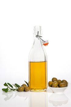 Olive oil in glass bottle, olives in bowl and fresh olive branch and leaves isolated on white background. Culinary cooking.