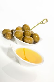 Delicious organic extra virgin olive oil and ripe olives in bowls isolated on white background. Traditional italian cuisine.