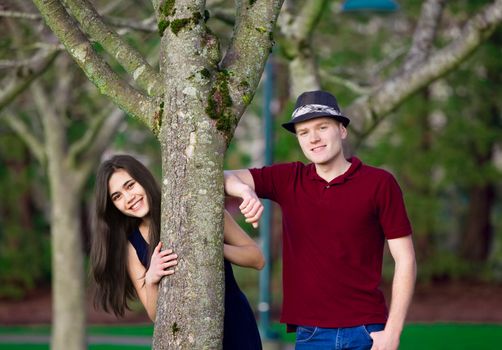 Young happy interracial couple standing together  by tree