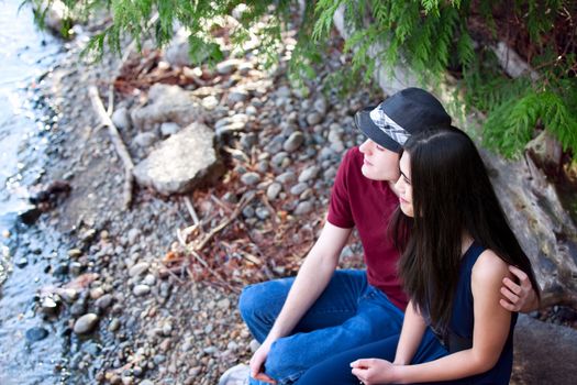 Happy young interracial couple sitting together by lake shore