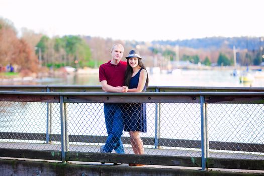 Young interracial couple standing together on wooden pier over lake