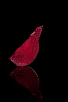 Healthy delicious beet piece isolated on black background with reflection. Luxurious vegetable concept.