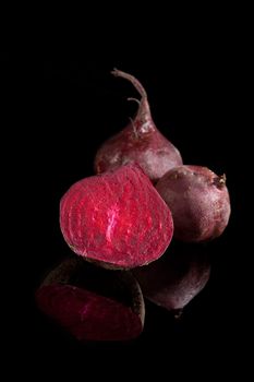 Dark beet background. Half beet isolated on black background with reflection. Luxurious dark vegetable background.