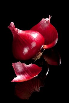 Red onion isolated on black background with reflection. Luxurious food ingredient background.