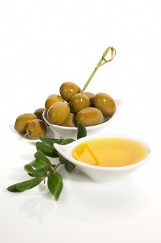 Green olives and extra virgin oliver oil with olive twig isolated on white background. Traditional olive background.