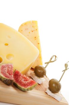 Delicious cheese background with various cheese sorts, fig, green olives on chopping board on white. Culinary appetizer background.