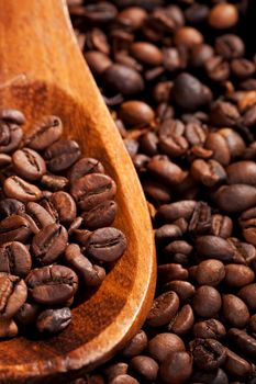 Coffee beans on wooden spoon on coffee beans background. Coffee still life.