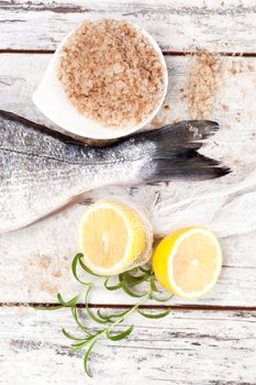 Fish tail with lemon, sea salt, fresh lemon on white wooden textured background. Culinary seafood background in white.