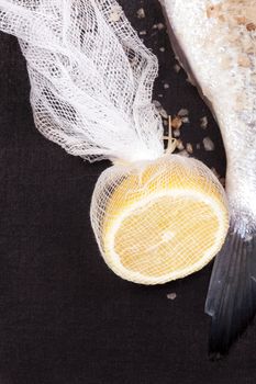 Lemon half with fish tail isolated on black background. Culinary luxurious seafood concept.
