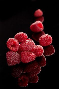 Delicious ripe raspberries isolated on black background. Luxurious summer fruits.