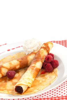 Delicious pancakes with raspberries and cream on plate isolated on white. Traditional sweet dessert in red and white. Culinary eating.