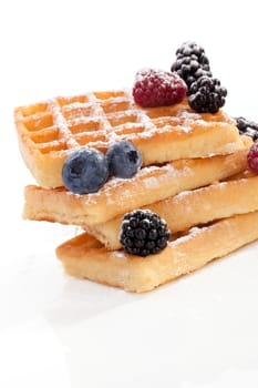 Luxurious waffle pile with fresh ripe berries isolated on white background. Culinary traditional gourmet sweet dessert concept.