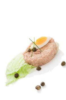 Tuna steak with fresh lettuce salad, capers and egg isolated on white background with reflection. Culinary fish, seafood concept.